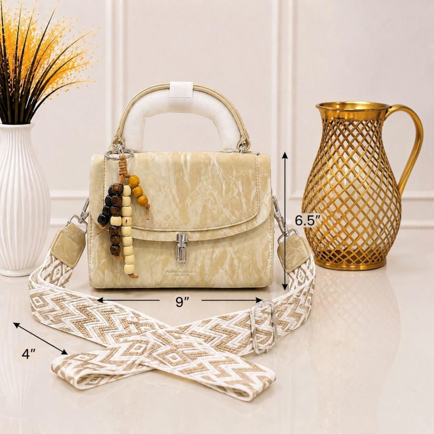Evnique structured beige marble-effect handbag with a beaded charm and detachable woven guitar-style crossbody strap.