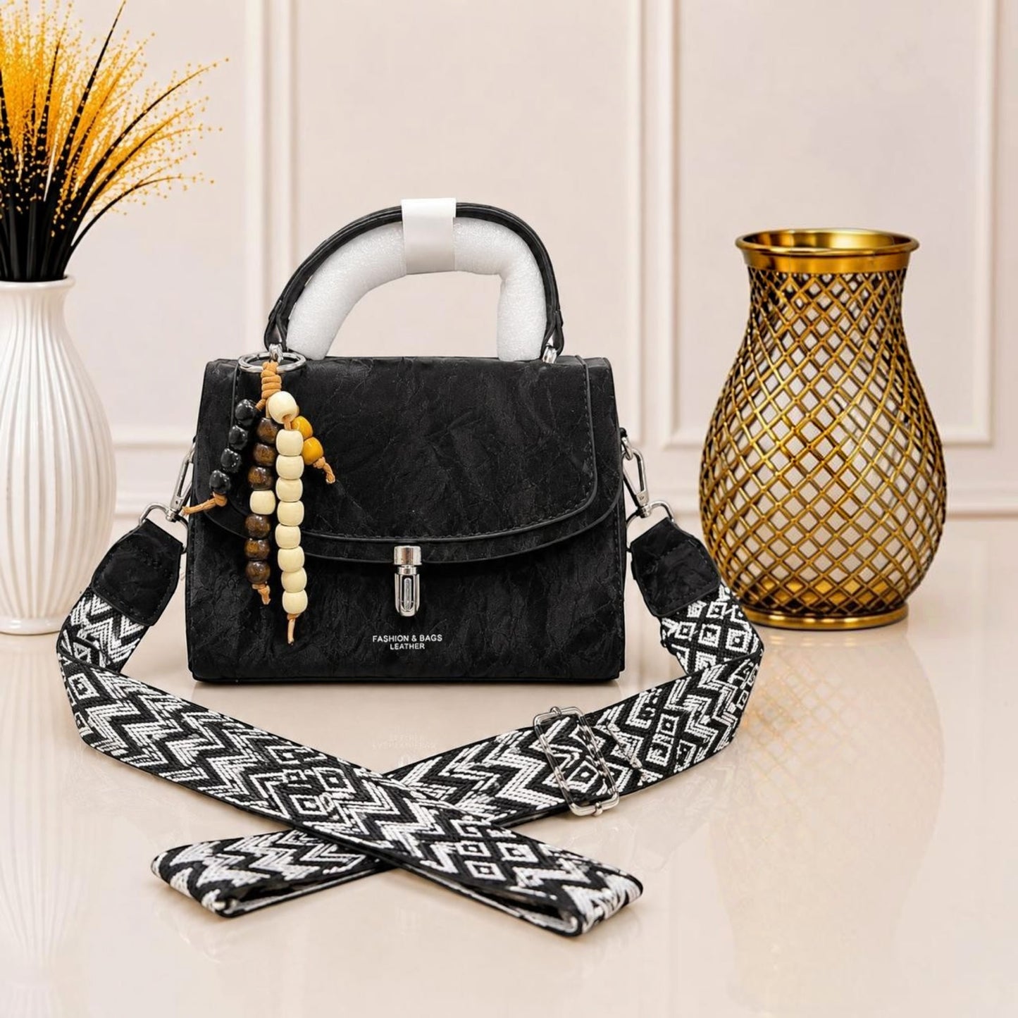 Evnique black marble-effect structured handbag with a beaded charm and detachable patterned woven crossbody strap.
