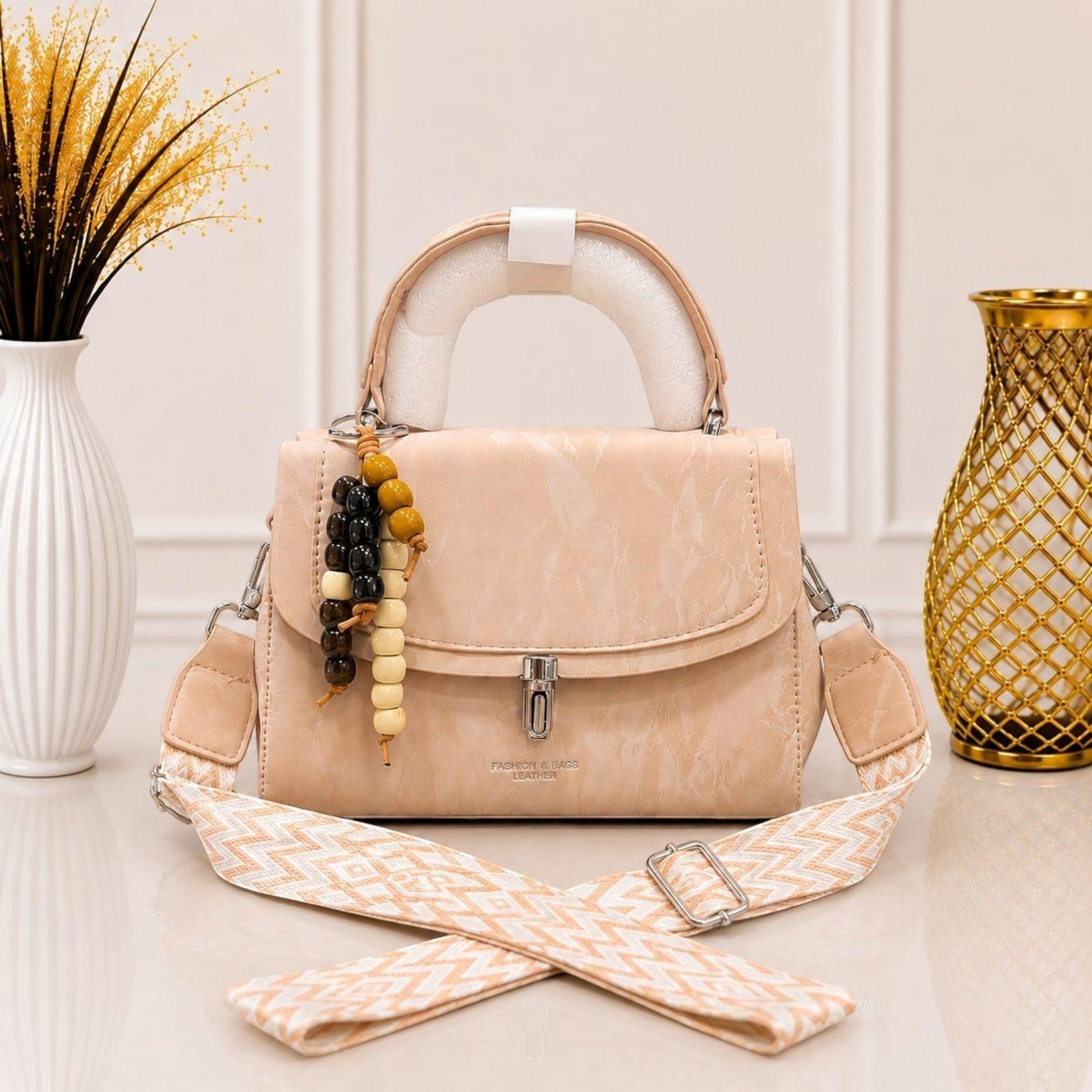 Evnique beige marble-effect structured top handle handbag with a beaded charm and woven guitar-style crossbody strap.