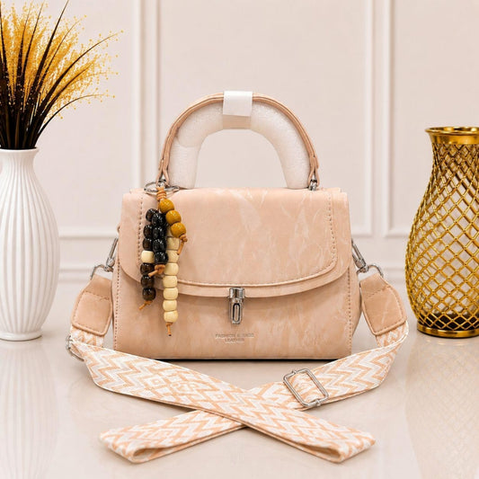 Evnique beige marble-effect structured top handle handbag with a beaded charm and woven guitar-style crossbody strap.