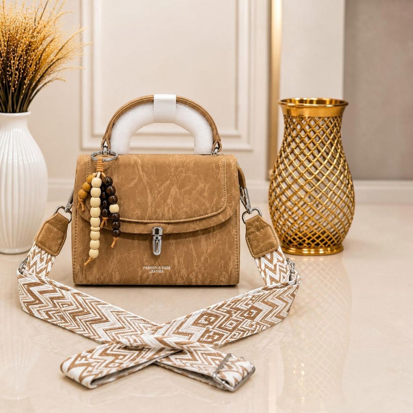 Evnique tan marble-effect structured handbag with a beaded charm and detachable woven guitar-style crossbody strap.