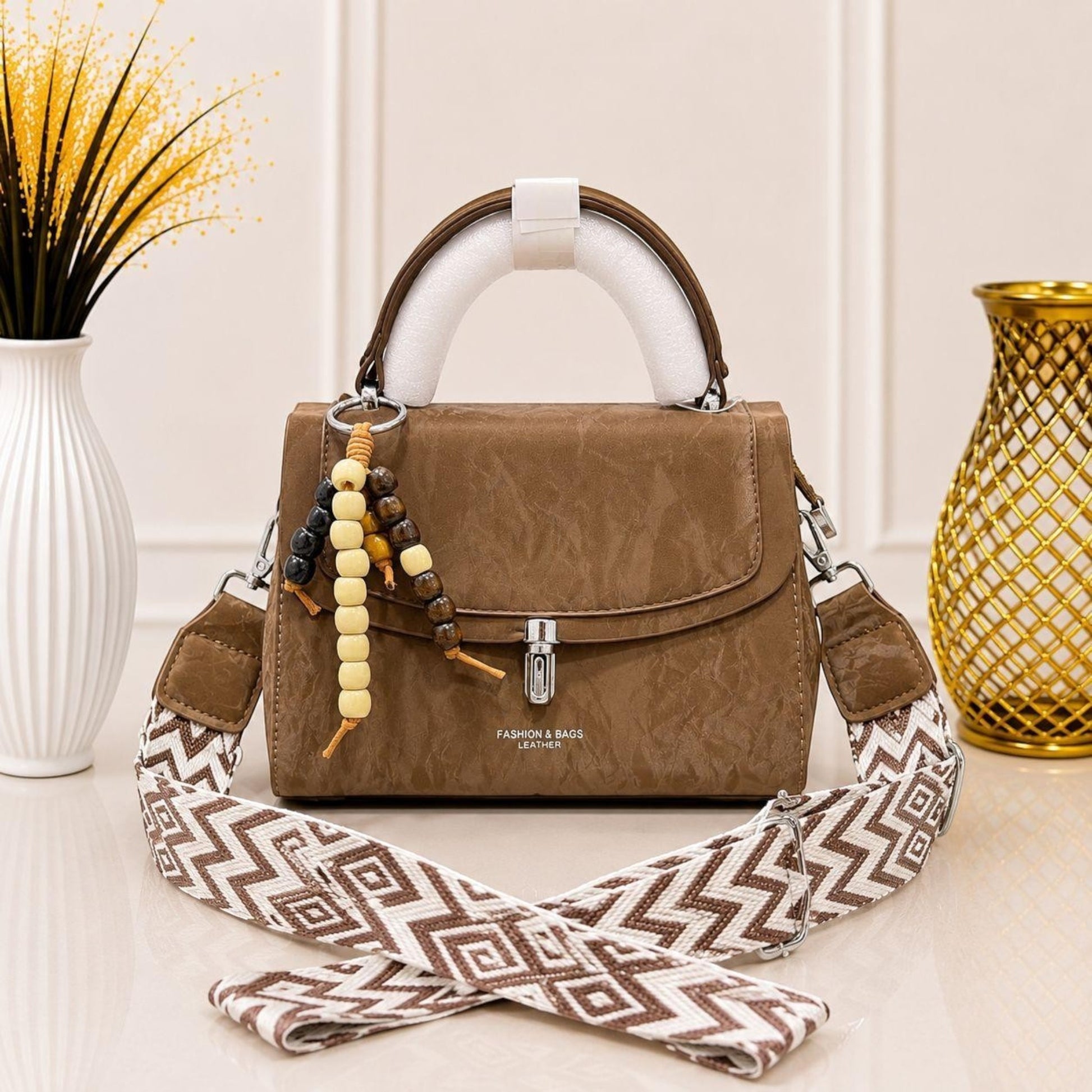 Evnique brown marble-effect structured top-handle handbag with a decorative beaded charm and woven guitar strap.